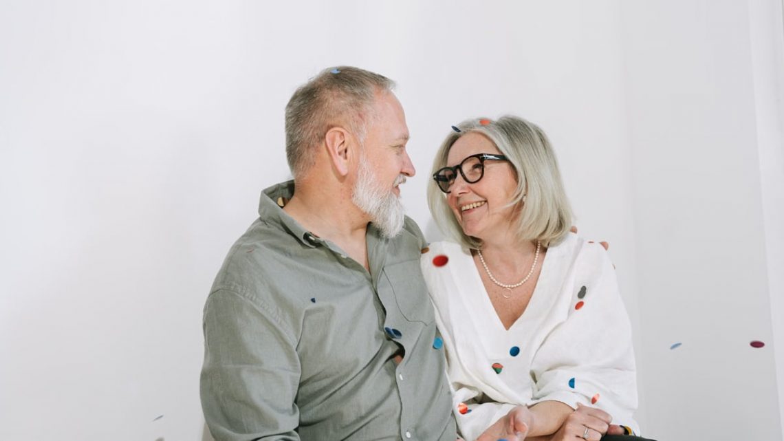 Senior couple enjoying a joyful moment with confetti indoors, portraying happiness and love.